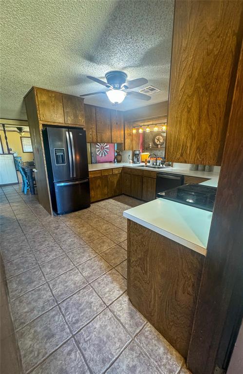 kitchen featuring ceiling fan, sink, black appliances, and a textured ceiling