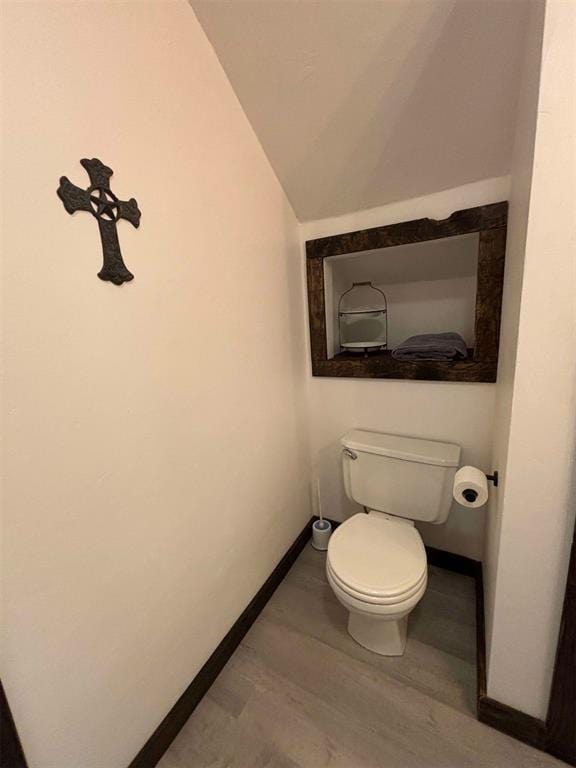 bathroom with hardwood / wood-style floors, vaulted ceiling, and toilet