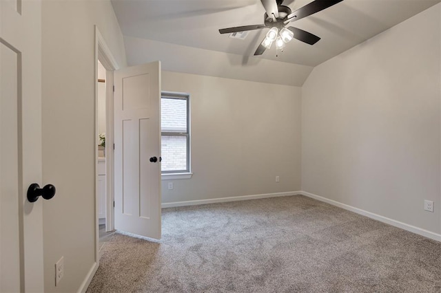 carpeted spare room with lofted ceiling, a ceiling fan, and baseboards