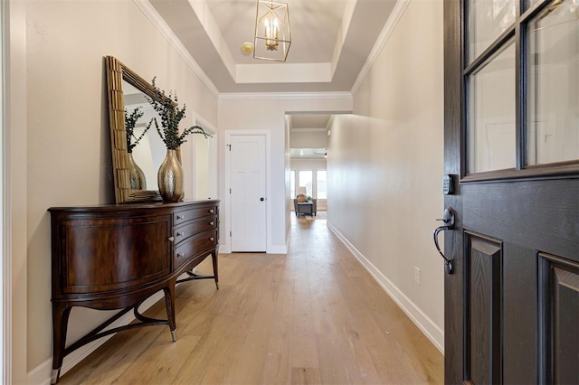 entryway featuring light wood finished floors, baseboards, an inviting chandelier, a tray ceiling, and crown molding