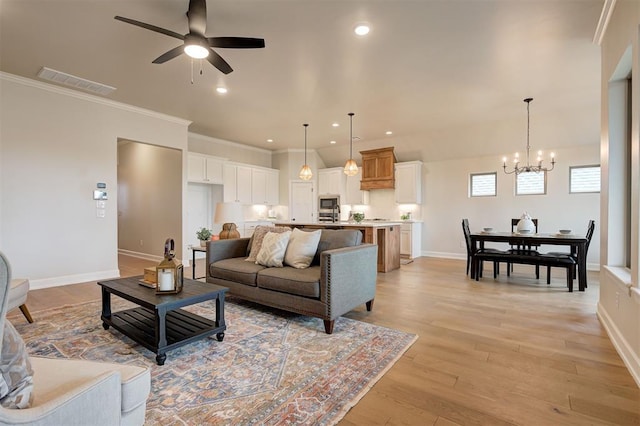 living area featuring visible vents, crown molding, light wood-style flooring, and baseboards