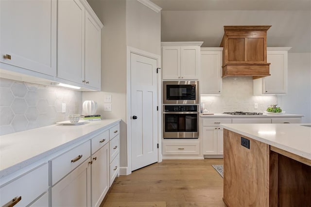 kitchen featuring stainless steel appliances, light countertops, light wood-style flooring, and white cabinets