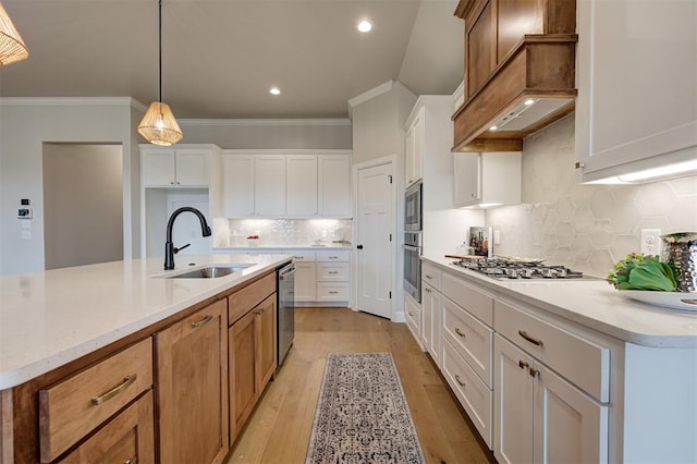 kitchen with light wood-style flooring, ornamental molding, stainless steel appliances, light countertops, and a sink