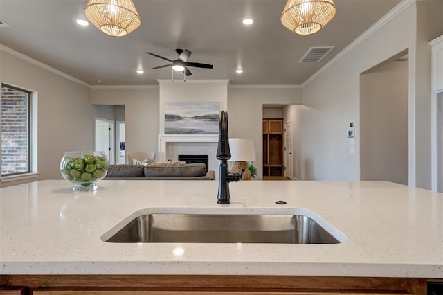 kitchen featuring pendant lighting, a fireplace, visible vents, open floor plan, and a sink