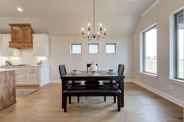 dining area with visible vents, baseboards, vaulted ceiling, light wood finished floors, and an inviting chandelier