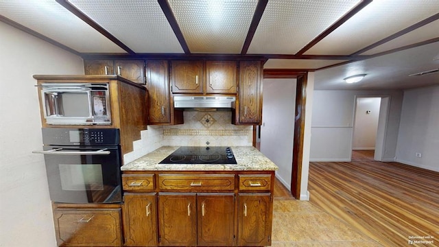 kitchen with tasteful backsplash, black appliances, and light hardwood / wood-style floors