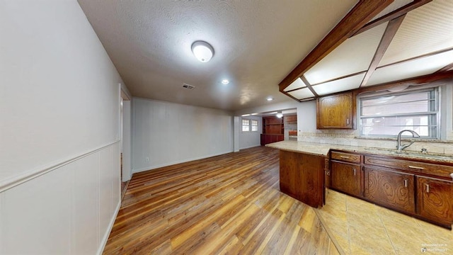 kitchen with light hardwood / wood-style floors, sink, a textured ceiling, and tasteful backsplash