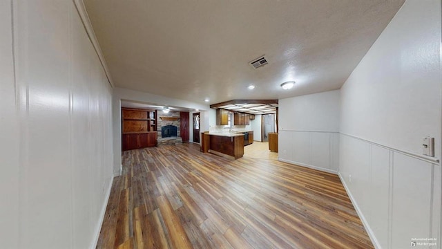 unfurnished living room with hardwood / wood-style floors, built in shelves, and a fireplace