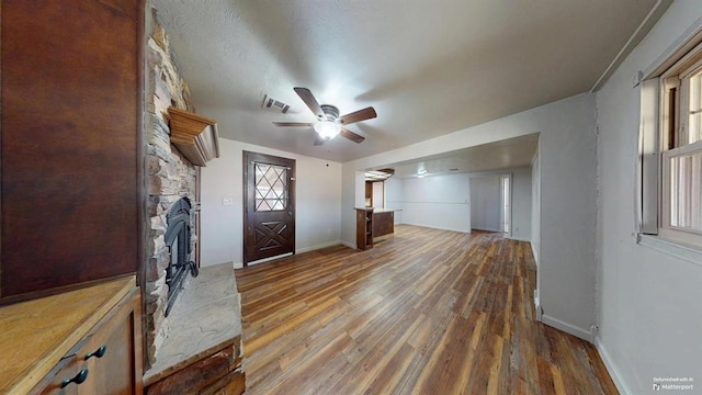 entryway with hardwood / wood-style floors, ceiling fan, and a fireplace