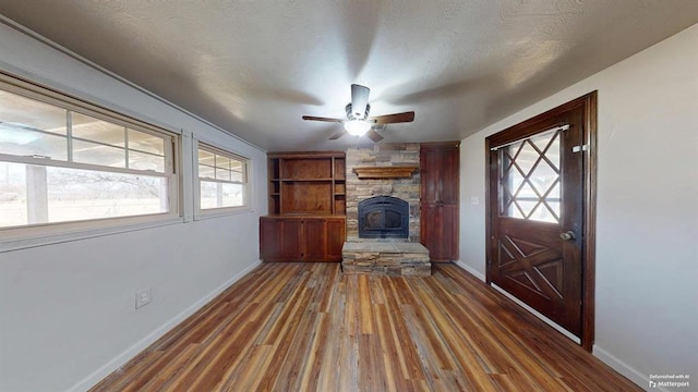 entrance foyer featuring ceiling fan, dark wood-type flooring, a textured ceiling, and a stone fireplace