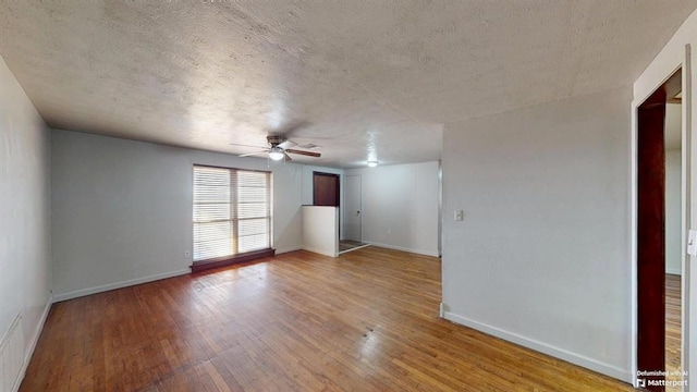 empty room with light hardwood / wood-style floors, ceiling fan, and a textured ceiling