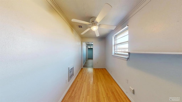 hallway with heating unit, light wood-type flooring, and crown molding