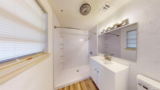 bathroom featuring toilet, vanity, a shower, and wood-type flooring