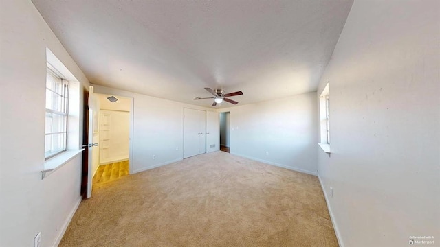 unfurnished bedroom with light carpet, ceiling fan, and a closet