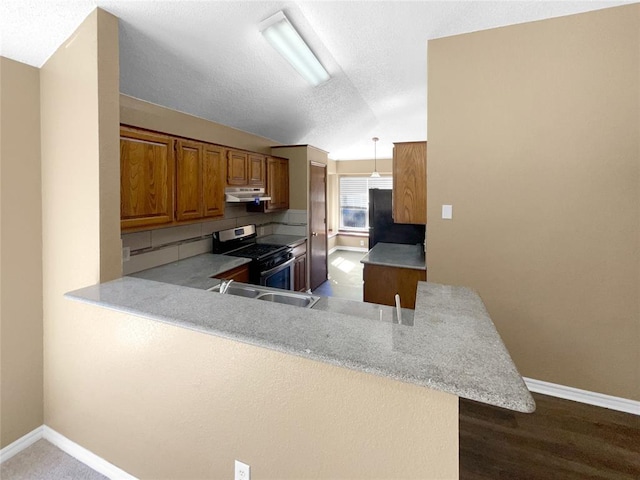 kitchen featuring gas range, dark hardwood / wood-style floors, kitchen peninsula, decorative light fixtures, and vaulted ceiling