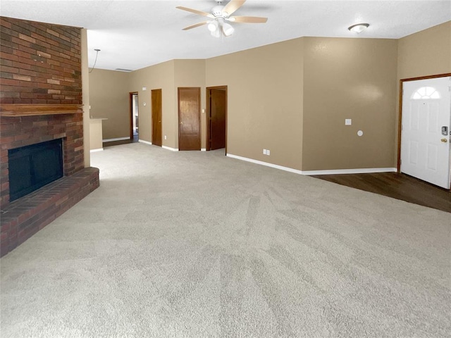 unfurnished living room featuring carpet, a brick fireplace, and ceiling fan