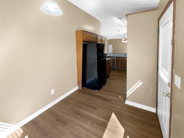 kitchen featuring black fridge, stainless steel dishwasher, ornamental molding, dark wood-type flooring, and an inviting chandelier