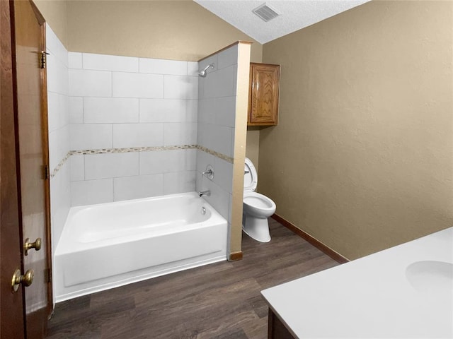 full bathroom with a textured ceiling, tiled shower / bath combo, vanity, wood-type flooring, and toilet