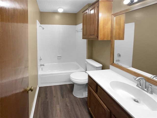 full bathroom with shower / bathing tub combination, vanity, hardwood / wood-style flooring, toilet, and a textured ceiling