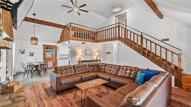 living room featuring high vaulted ceiling, wooden walls, hardwood / wood-style flooring, ceiling fan, and beamed ceiling