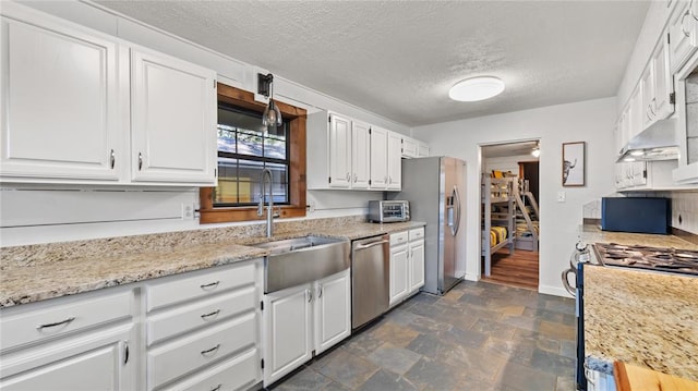 kitchen with white cabinetry, light stone counters, a textured ceiling, and appliances with stainless steel finishes