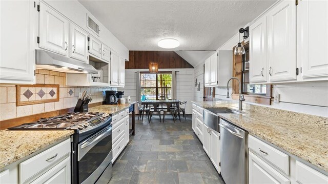 kitchen featuring white cabinets, decorative light fixtures, light stone counters, and appliances with stainless steel finishes