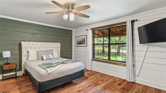 bedroom with wood-type flooring, ceiling fan, and wood walls