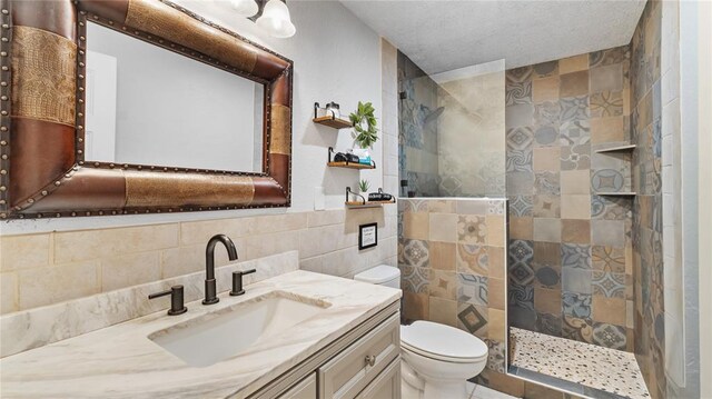 bathroom featuring a tile shower, vanity, toilet, and tile walls