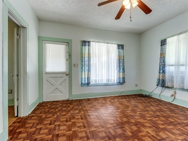 entrance foyer featuring ceiling fan, a textured ceiling, and dark parquet floors