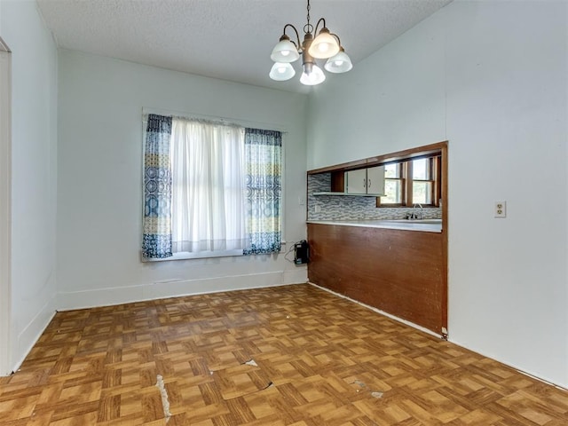 spare room featuring a notable chandelier, sink, a textured ceiling, and light parquet floors