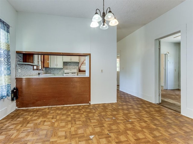 kitchen featuring backsplash, light parquet floors, an inviting chandelier, hanging light fixtures, and white cabinetry