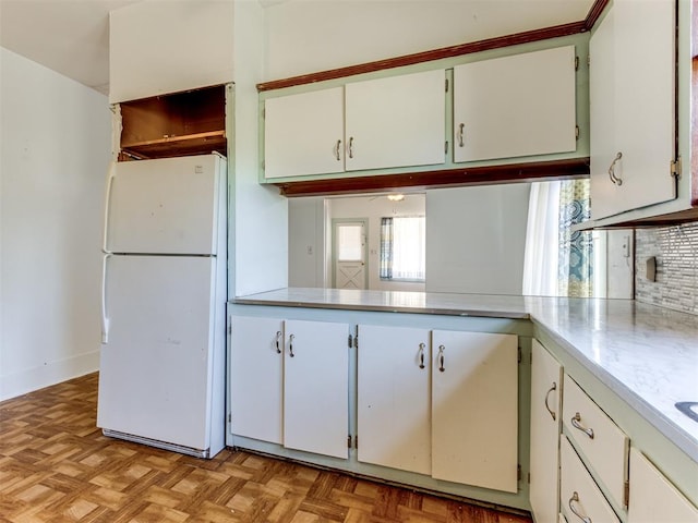 kitchen with white refrigerator, white cabinetry, and light parquet flooring