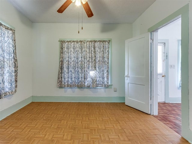 empty room featuring ceiling fan, a textured ceiling, and light parquet floors