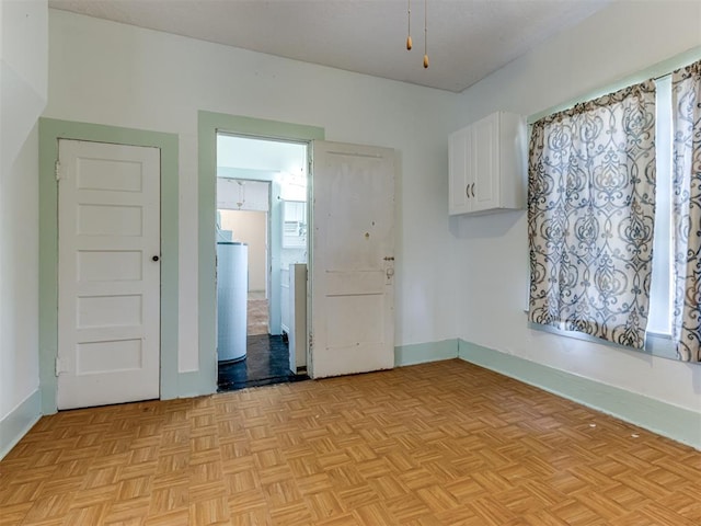 empty room with ceiling fan, washer / dryer, and light parquet flooring