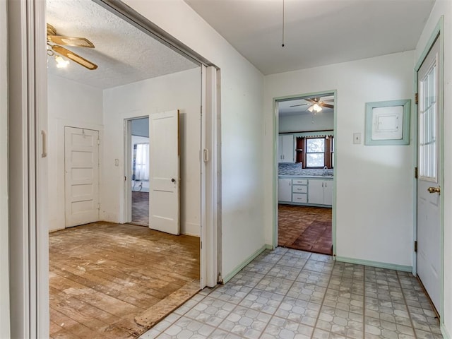 hallway with a textured ceiling and light wood-type flooring