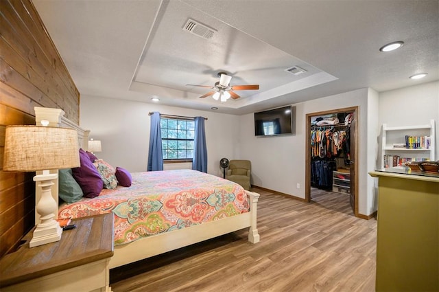 bedroom featuring a closet, a spacious closet, ceiling fan, and wood walls