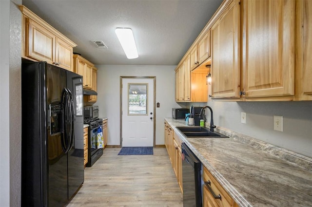 kitchen featuring sink, black appliances, light brown cabinets, and light wood-type flooring