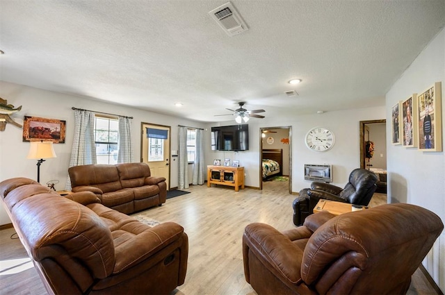 living room featuring a textured ceiling, light wood-type flooring, and ceiling fan