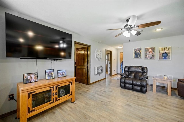 living room featuring heating unit, ceiling fan, and light hardwood / wood-style flooring