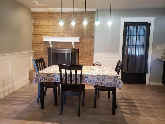 dining space with a fireplace, wood-type flooring, and crown molding