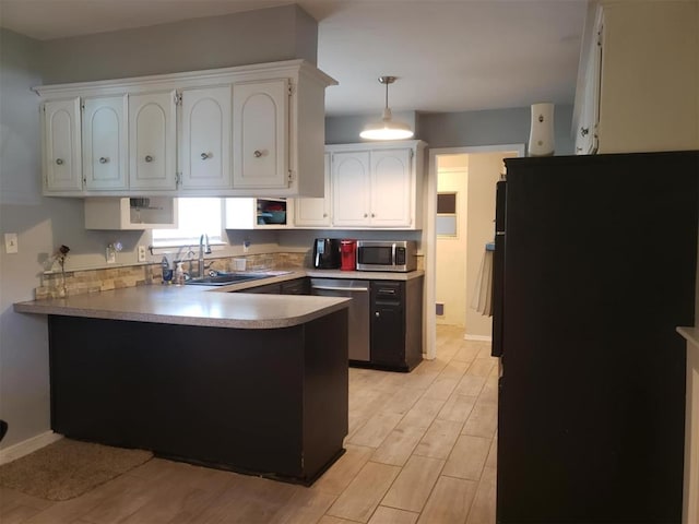 kitchen with sink, hanging light fixtures, light hardwood / wood-style floors, white cabinetry, and stainless steel appliances