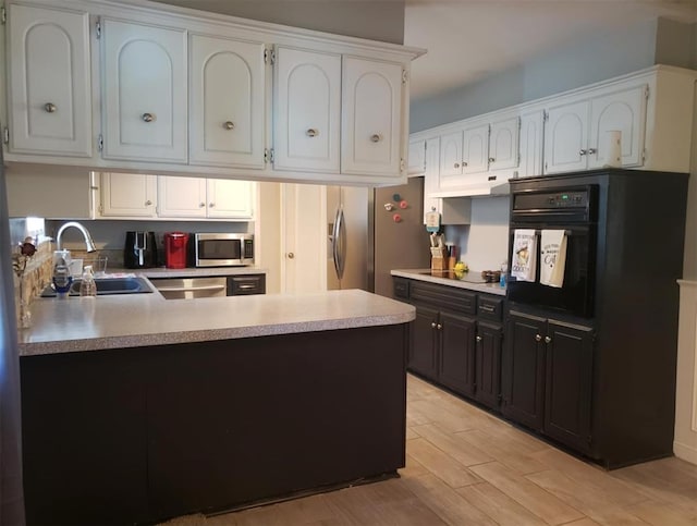 kitchen with white cabinets, black appliances, sink, and light hardwood / wood-style flooring