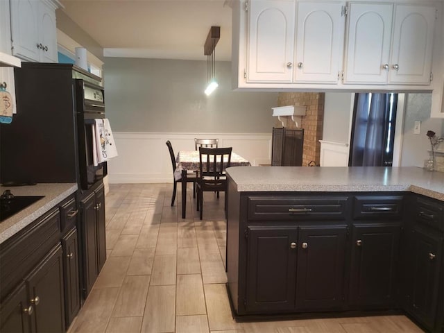 kitchen with white cabinets, kitchen peninsula, oven, and hanging light fixtures