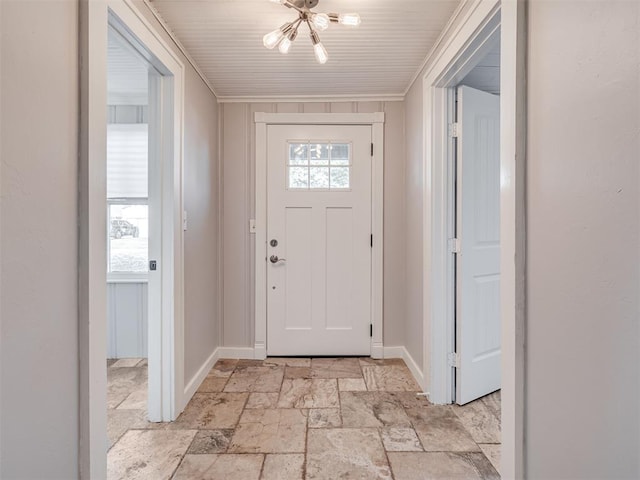 entryway with a notable chandelier and crown molding