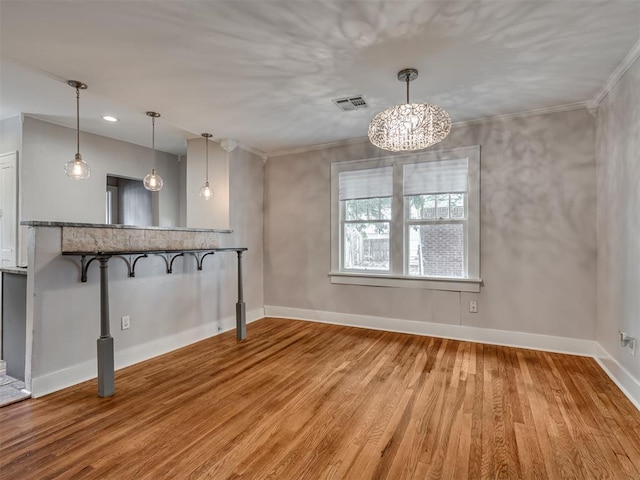 unfurnished dining area with wood-type flooring, an inviting chandelier, and crown molding