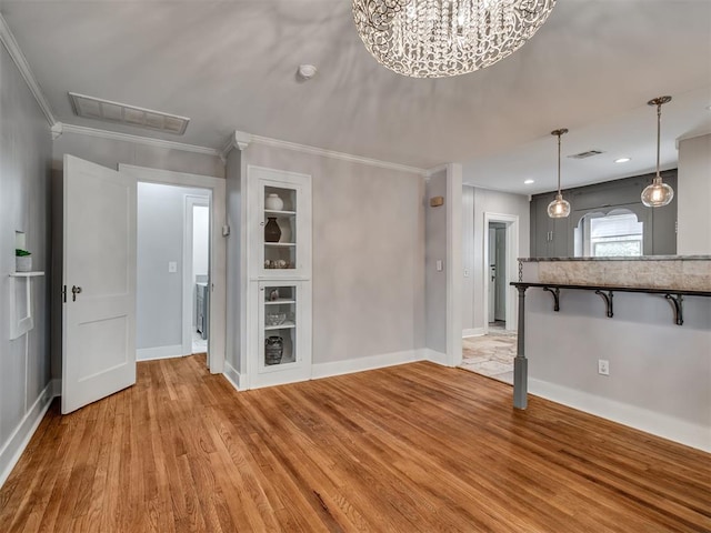 unfurnished living room with a notable chandelier, light wood-type flooring, and ornamental molding