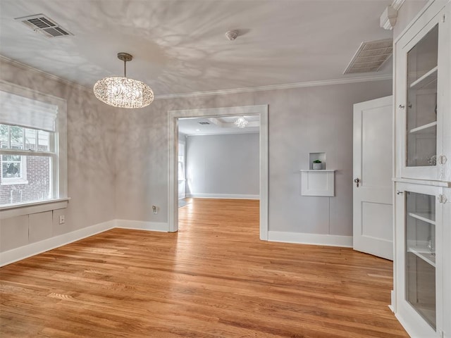 interior space featuring light hardwood / wood-style floors, ornamental molding, and a notable chandelier