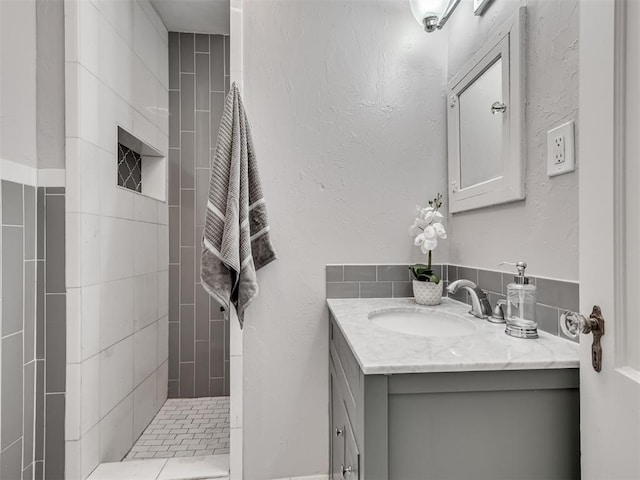 bathroom featuring a tile shower and vanity