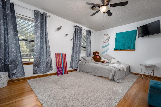 bedroom with ceiling fan, wood-type flooring, and a textured ceiling