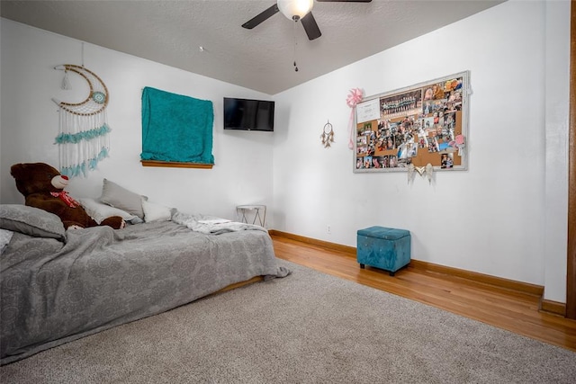 bedroom with ceiling fan, hardwood / wood-style floors, and a textured ceiling